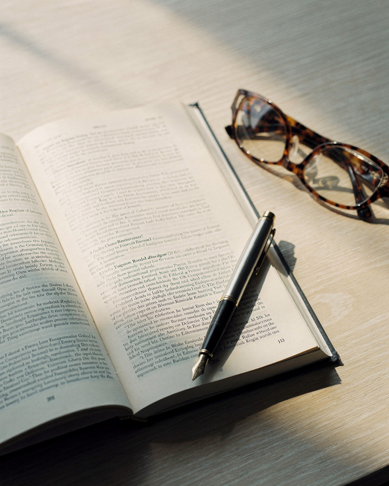 An open Federal Register volume on a pale wood surface with morning light raking across the page and a pen at rest.