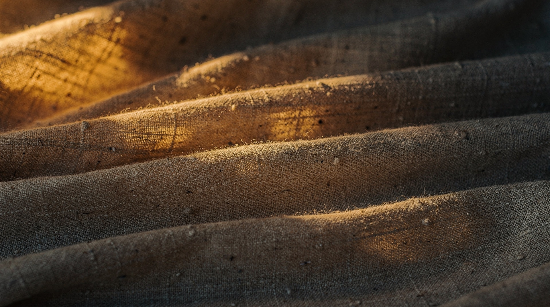 Soft folds of warm-amber and oat linen in raking golden light