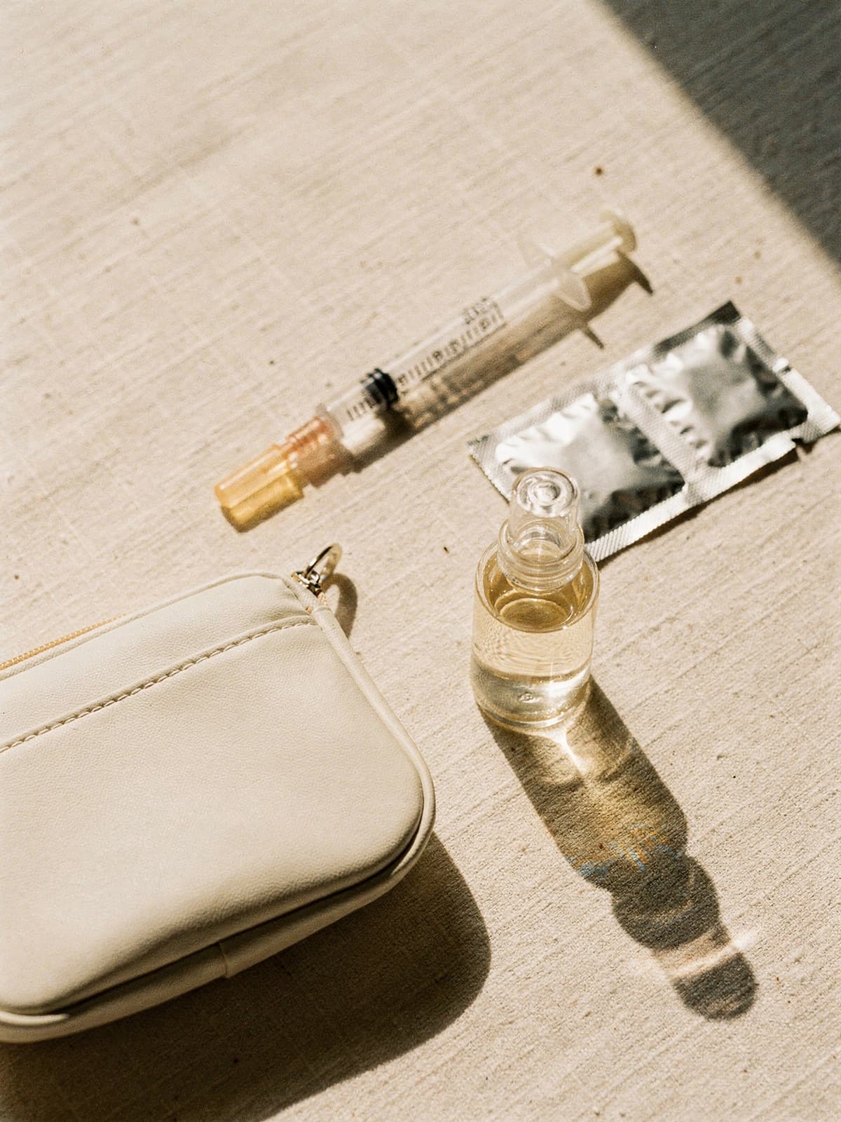 Unbranded NAD+ vial and syringe on cream linen in bright morning sunlight