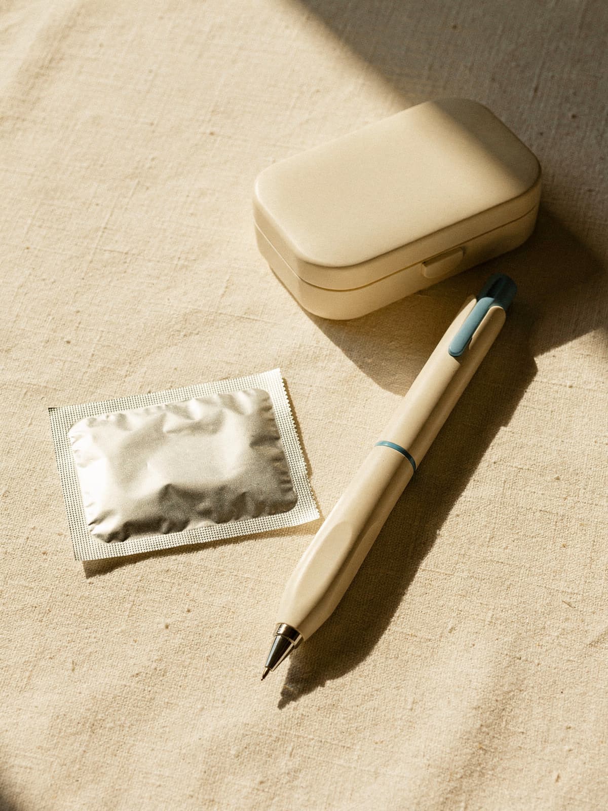 Unbranded GLP-1 injector pen on cream linen in bright morning sunlight