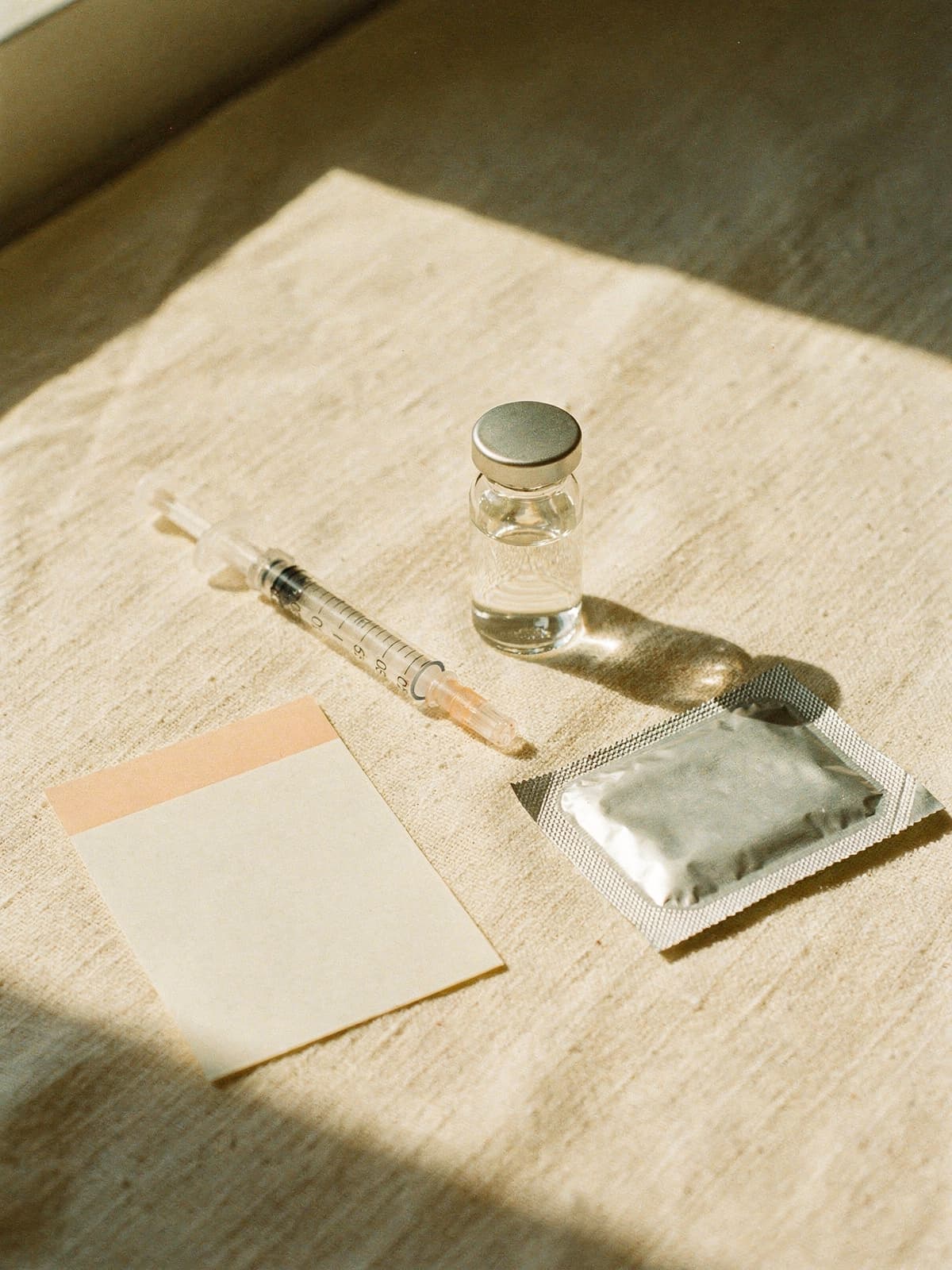 Unbranded peptide therapy kit on warm cream linen in bright morning light